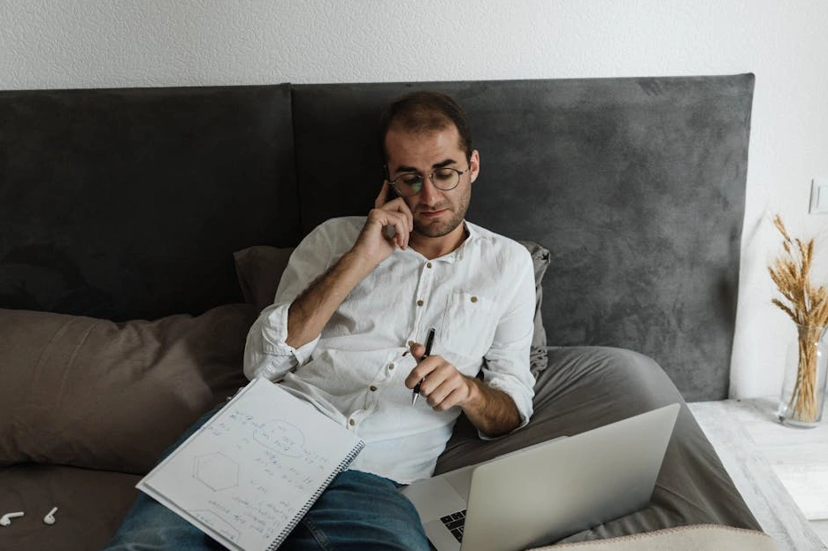 Persona che scrive su un quaderno in un ambiente luminoso e naturale.